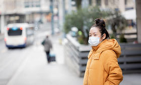 Asian woman wearing mask waiting for bus