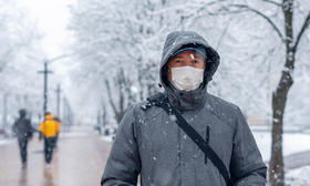 man wearing mask winter coat walking in snow