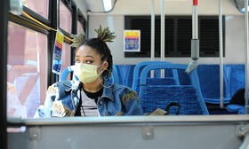 African American woman wearing mask riding bus