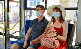Couple holding hands wearing masks riding the bus